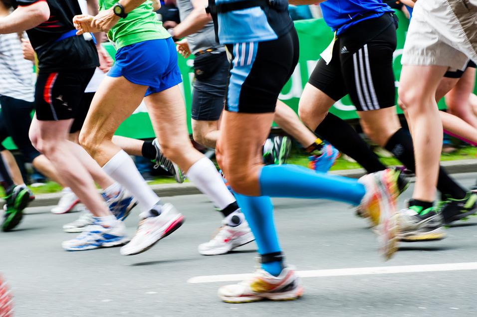 Bunte Laufschuhe rennen in einem Marathon, während Zuschauer im Hintergrund auf der Strecke stehen.